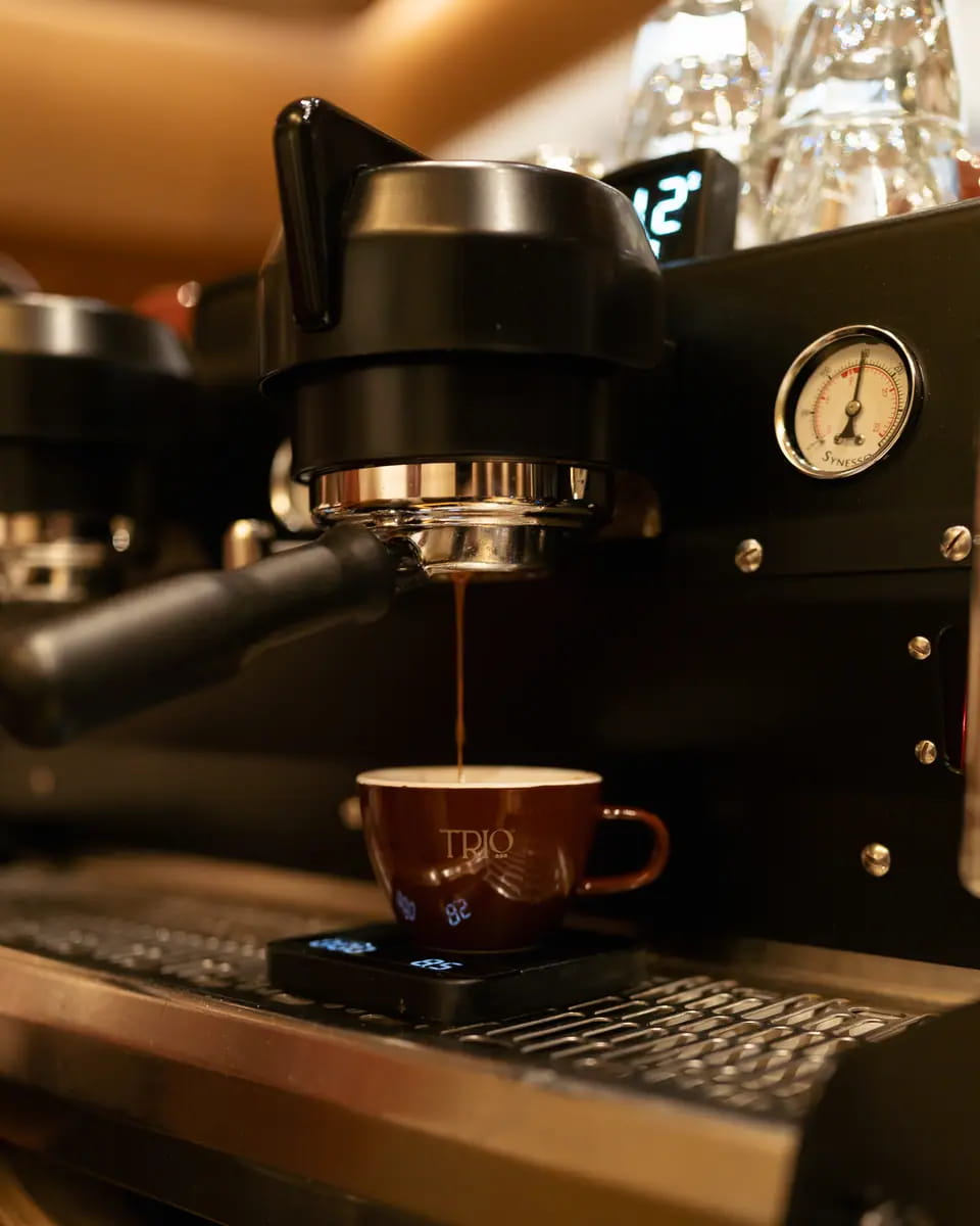 Espresso running into a terracotta cup on a brass-trimmed machine