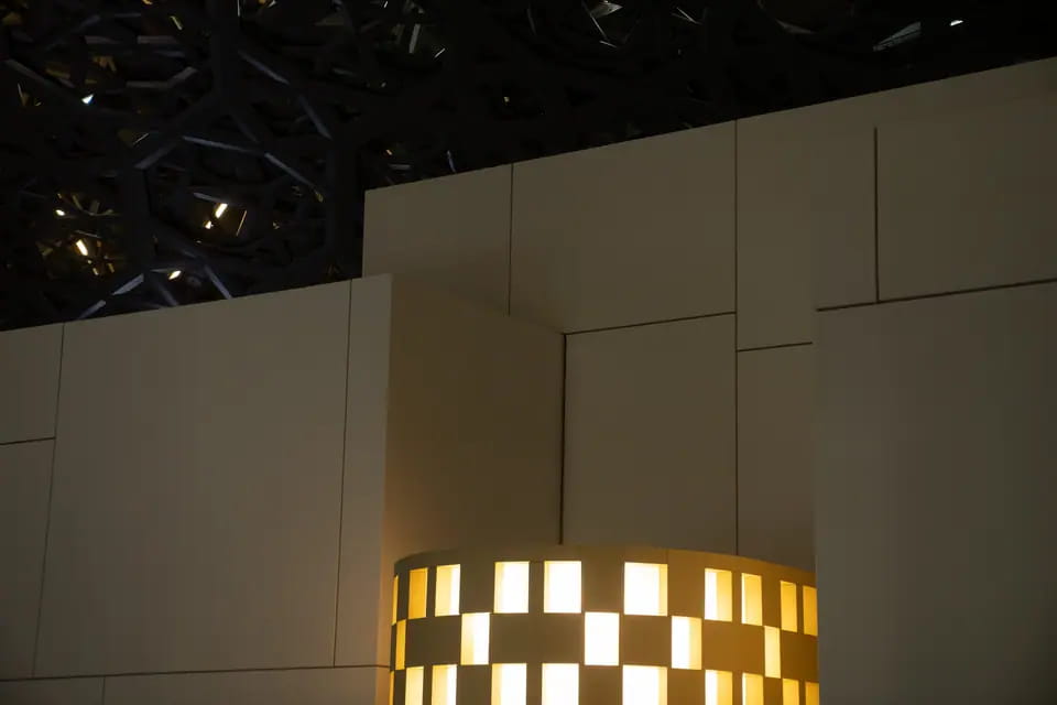 After dark the checkerboard lantern glows low between tall cream wall panels, the dome lattice black above