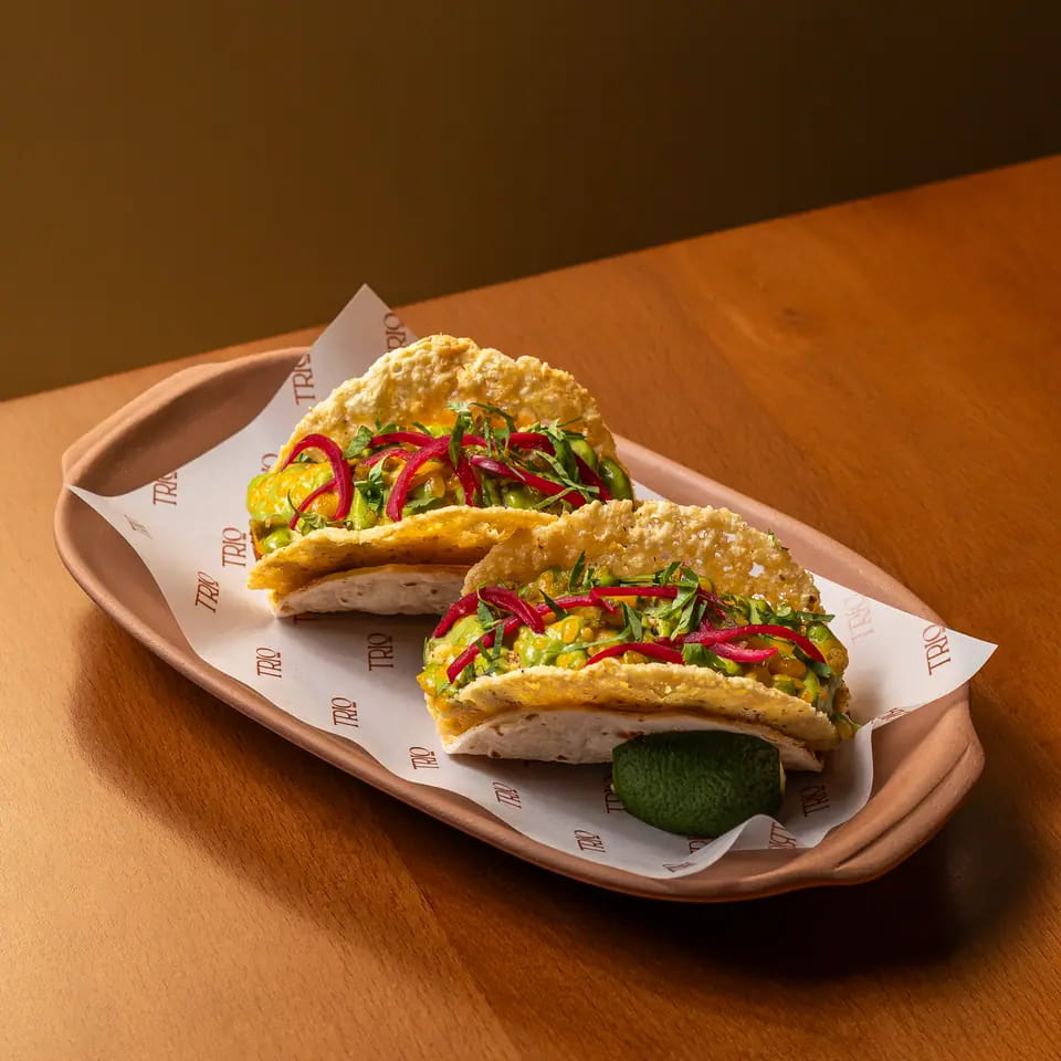 Two breakfast tacos with lime on a TRIO paper-lined tray
