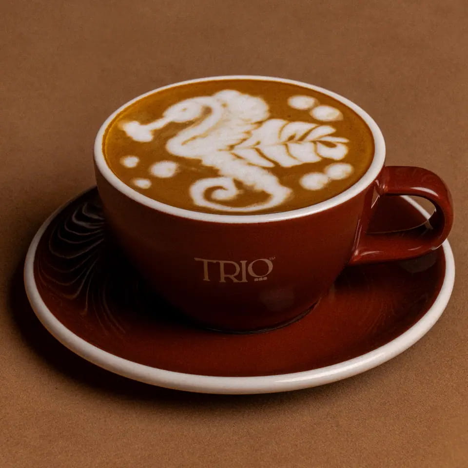 Cappuccino with seahorse latte art in a burgundy TRIO cup