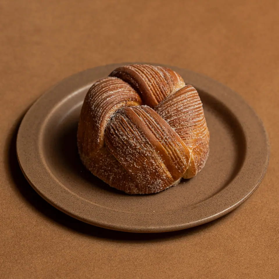 Knotted cardamom bun on a stoneware plate