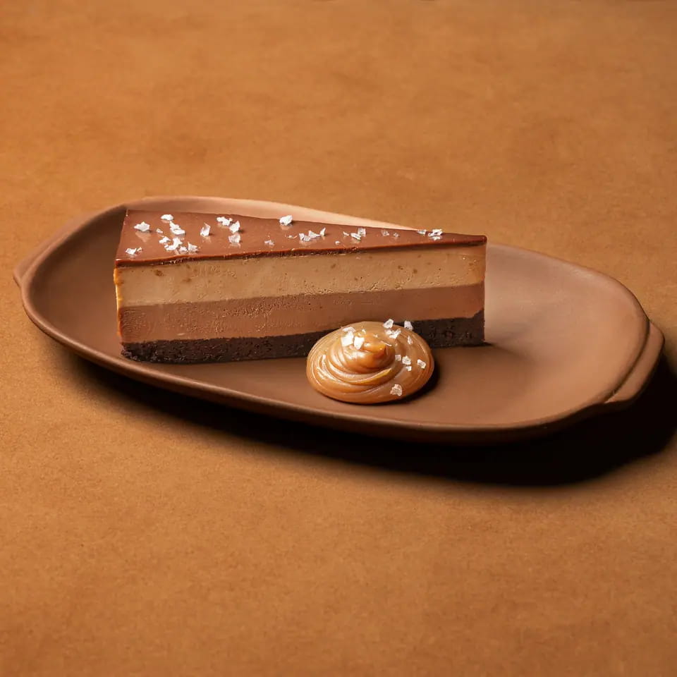 Slice of layered chocolate peanut butter cake with a caramel dollop