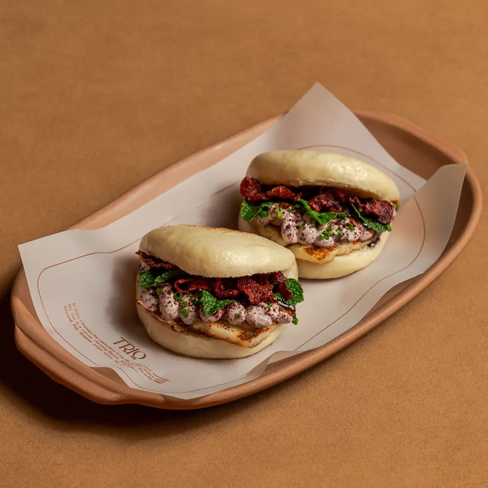 Two crispy beetroot halloumi bao buns on a lined tray