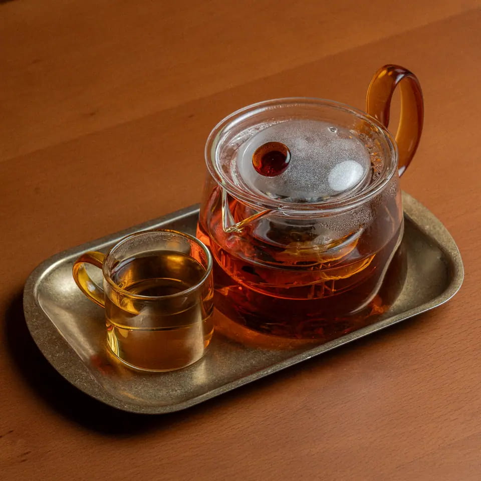 Earl Grey tea in a glass teapot with cup on a brass tray