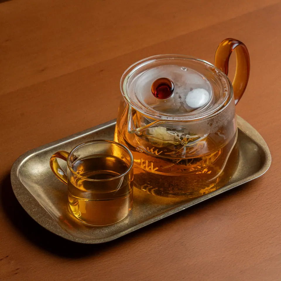 English Breakfast tea in a glass teapot with cup on a brass tray