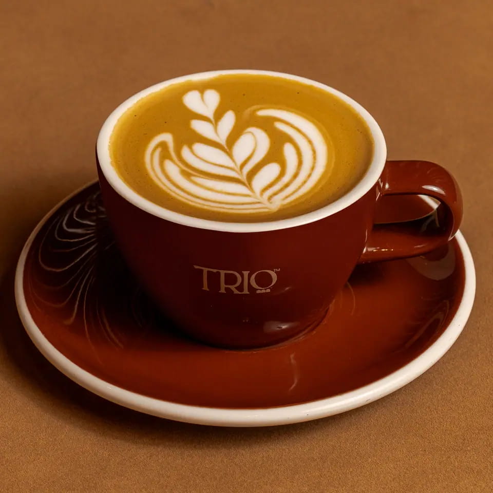 Flat white with rosetta latte art in a burgundy TRIO cup