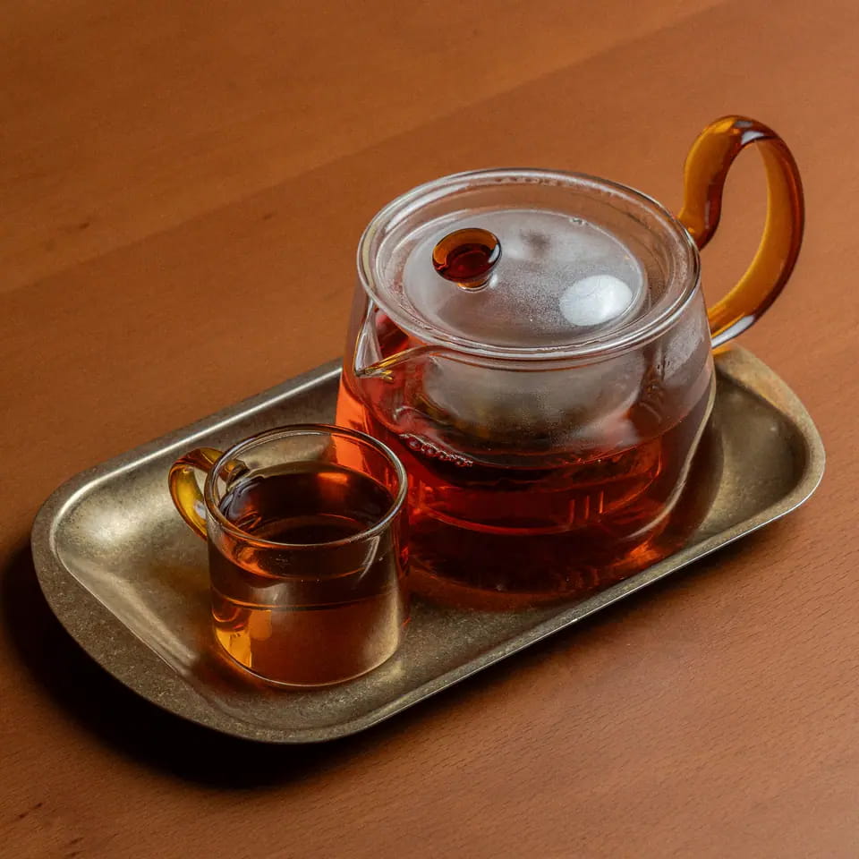Oriental tea in a glass teapot with cup on a brass tray