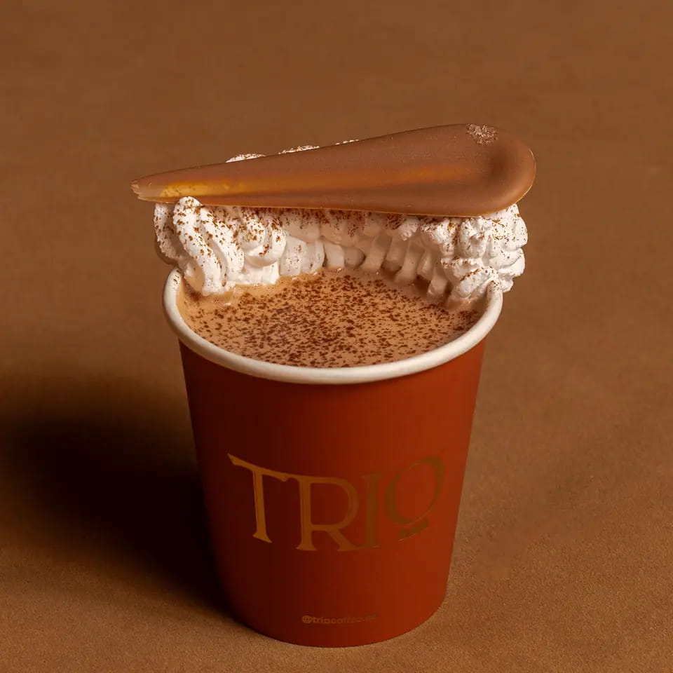 Salted hot chocolate with cream and a chocolate tuile in a TRIO paper cup