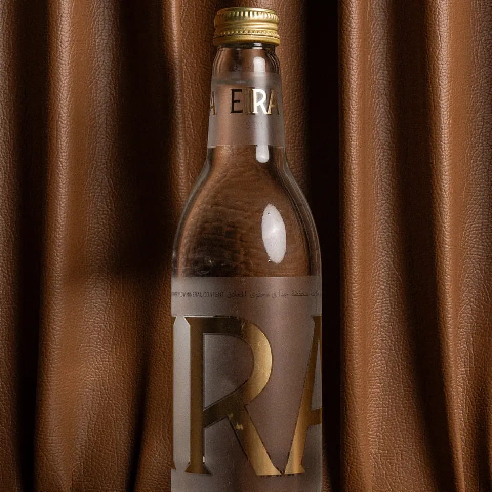 Bottle of still water against a brown curtain