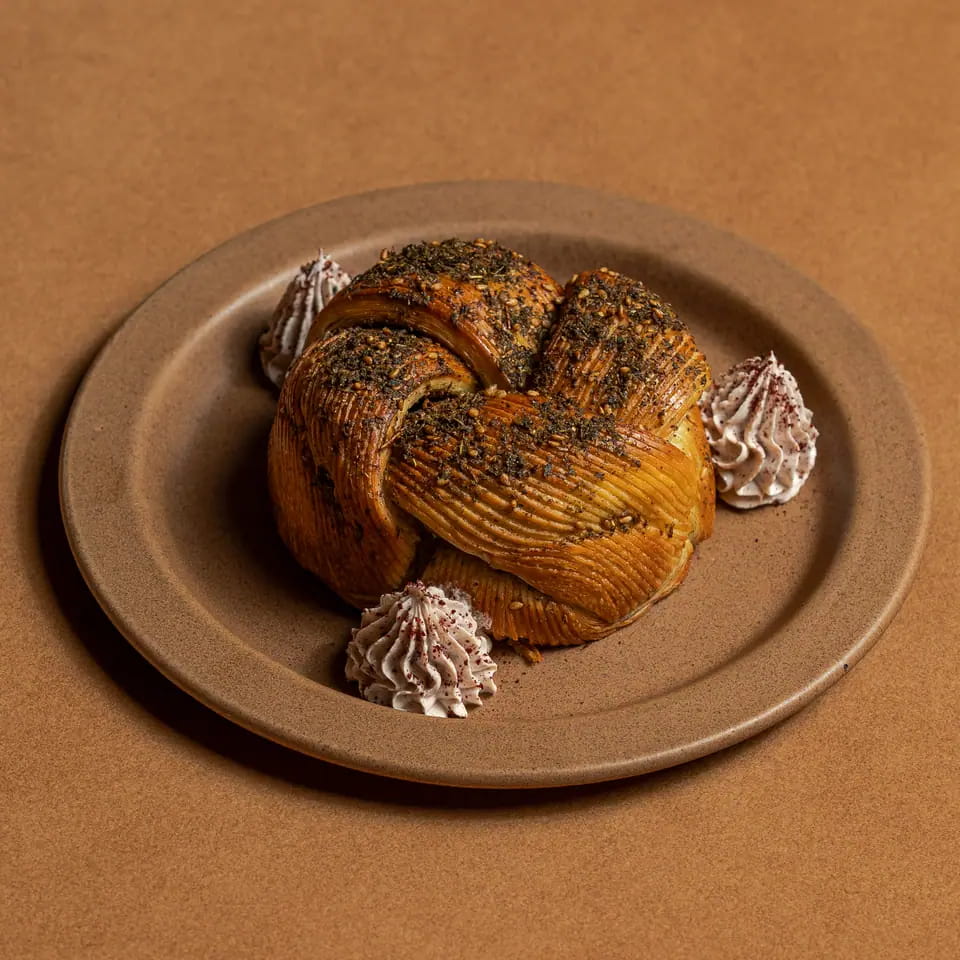 Zaatar bun with labneh dollops on a stoneware plate